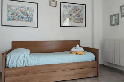 a bedroom with a wooden bed with blue sheets and pictures at Casa del Grecale in Isola delle Femmine