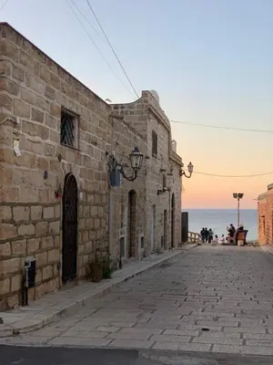 a stone building on a street next to the ocean at Villa Serendipity Terrasini in Terrasini