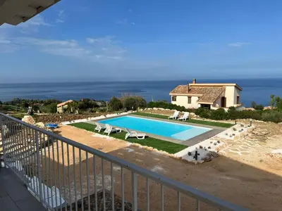 a swimming pool in front of a house with the ocean at Apt Perterrepermari a 2 Km Da Riserva Dello Zingaro in Scopello