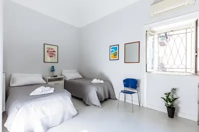 a bedroom with two beds and a blue chair at Casa Dante with Balcony by Wonderful Italy in Palermo