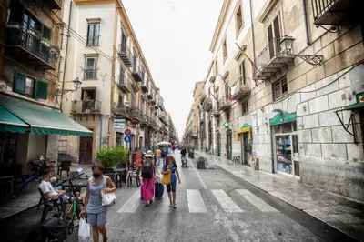 a group of people walking down a city street at Sol&Luna 1909 Tourist Location in Old Town in Palermo