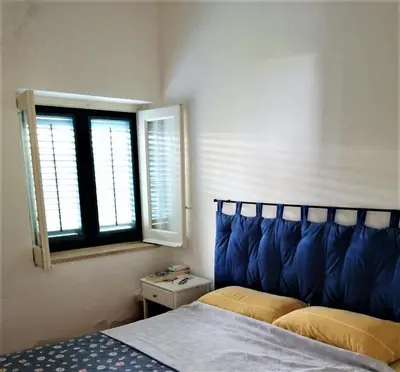 a bedroom with a bed with a blue headboard and a window at Luxury Villa just 50 mt from the beach, 10 minutes from the airport in Carini