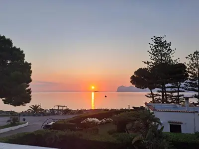 a sunset over the water with a building and trees at Luxury Villa just 50 mt from the beach, 10 minutes from the airport in Carini