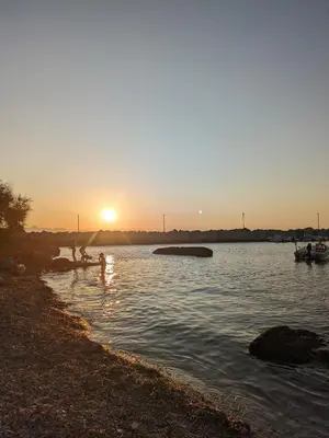 a group of people playing in the water at sunset at Nassa Apartment in Trappeto