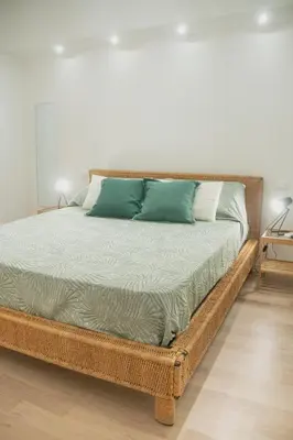 a large wicker bed with green pillows on it at Vicolo del Salto in Palermo