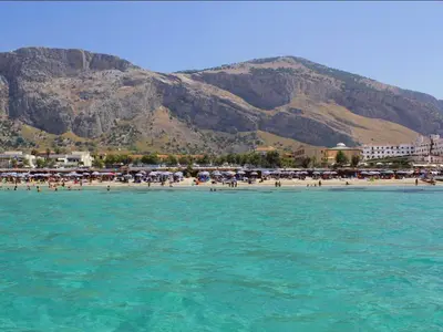 a beach with a bunch of people in the water at AR Palace Hotel - Palermo in Isola delle Femmine