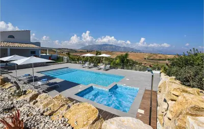 a swimming pool with chairs and umbrellas next to a building at Cozy Home In Partinico With Wifi in Partinico