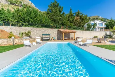 a swimming pool with chairs and a gazebo at Villa Romitello con Piscina Total Relax in Borgetto