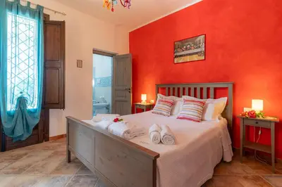 a bedroom with a large bed with red walls at Villa Romitello con Piscina Total Relax in Borgetto
