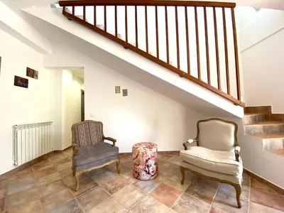 a living room with two chairs and a stair case at Villa Romitello con Piscina Total Relax in Borgetto