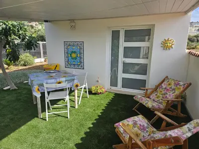 a patio with a table and chairs on the grass at CASA DEL SOLE in Alcamo