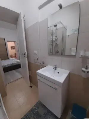 a white bathroom with a sink and a mirror at Rosina's flat in Palermo