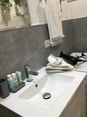 a white bathroom sink with towels and a mirror at La Casetta Paternò “Nel Cuore Pulsante di Palermo” in Palermo
