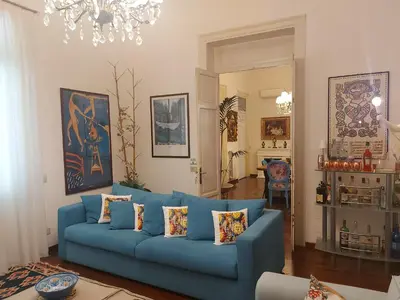 a living room with a blue couch and a chandelier at LE VELE in Palermo