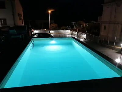 a swimming pool with blue lights on a roof at night at Seafront Apartment in Villa with Swimming Pool and Parking in Alcamo Marina