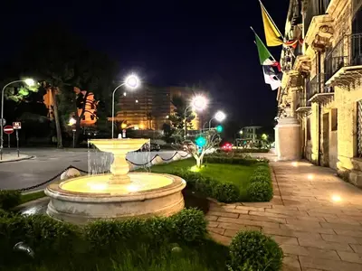 a fountain in the middle of a street at night at San Saverio Home in Palermo