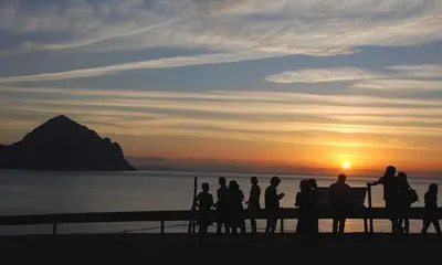 a group of people standing around watching the sunset at Cascina degli Ulivi in Castelluzzo