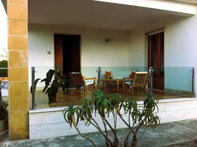 a porch of a house with a table and chairs at Villa On The Beach Spiaggia Plaia in Castellammare del Golfo