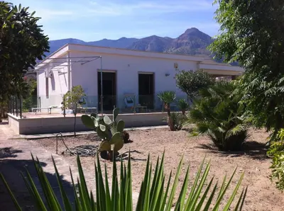 a white house with mountains in the background at Villa On The Beach Spiaggia Plaia in Castellammare del Golfo