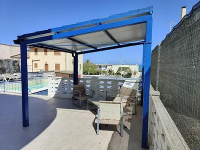 a pergola with chairs and a table on a balcony at Alcamo Marina Villa Pool in Alcamo Marina