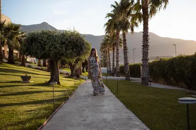 a woman in a dress walking down a sidewalk at Resort La Battigia Beach & Spa in Alcamo Marina