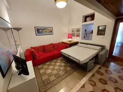 a living room with a red couch and a bed at Olivuzza Apartment in Palermo
