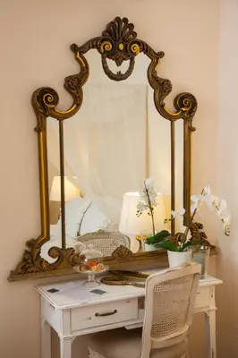 an ornate mirror on a table with a white desk with a mirror at Dimora Sinibaldi in Palermo