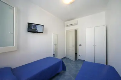 a bedroom with a blue bed and a tv on the wall at Venere ed Enea - Appartamenti Vista Mare in San Vito lo Capo