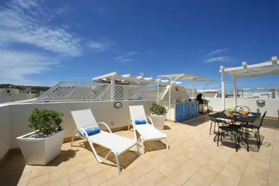 a patio with white chairs and a table on a roof at Venere ed Enea - Appartamenti Vista Mare in San Vito lo Capo