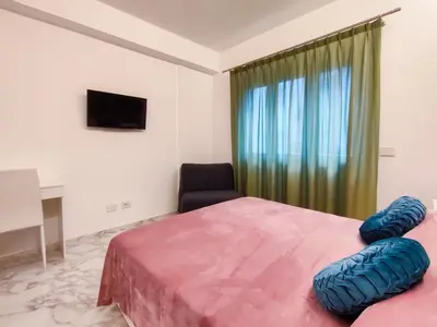 a bedroom with a bed and a chair and a window at Cubacalatafimi Rooms in Palermo