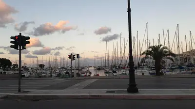 a street with traffic lights and a harbor with boats at Residenza Tarzanà in Palermo