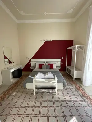 a bedroom with a bed and a red wall at Arricría Room Suite in Palermo