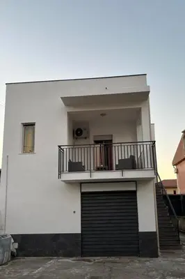 a white building with a gate and a balcony at Casa vacanze Ines in Carini