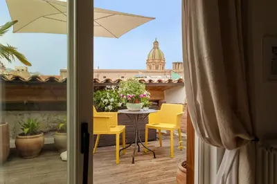 a balcony with yellow chairs and a table and umbrella at Sui Tetti di Balarm Boutique Rooms in Palermo