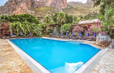 a swimming pool with chairs and a mountain in the background at Pietro 3 in San Vito lo Capo