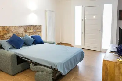 a bedroom with a bed with blue pillows and a couch at Casa Villafilippina in Palermo