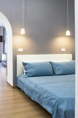 a bed with blue sheets in a room with two lights at Casa Villafilippina in Palermo