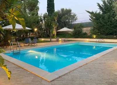 a large blue swimming pool with chairs and umbrellas at Villa Flora in Castellammare del Golfo