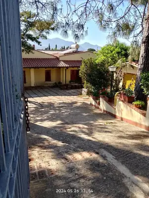 a driveway leading to a house with mountains in the background at Villa Flora in Castellammare del Golfo