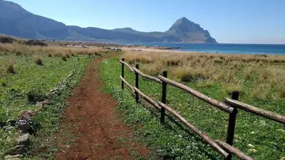 a dirt road next to a fence next to the ocean at MAKARI, Villetta Rocca Pirciata in Macari