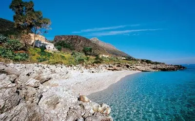 a beach with blue water and a rocky shore at MAKARI, Villetta Rocca Pirciata in Macari