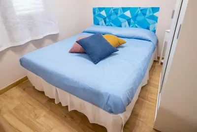 a bed with blue sheets and colorful pillows on it at Deluxe Sicily Villa in Buonfornello