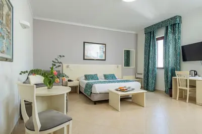 a hotel room with a bed and a table and a desk at Hotel Centrale Spa & Relax in Alcamo