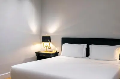 a white bed with a black headboard and a lamp at Grand Hotel Et Des Palmes in Palermo