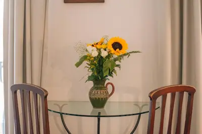 a vase of flowers on a glass table with two chairs at Boutique B&B Vintage in Palermo