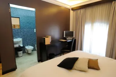 a bedroom with a bed and a desk and a bathroom at Ucciardhome Hotel in Palermo