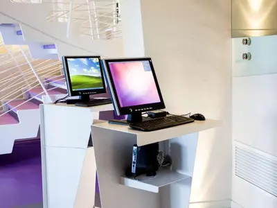 two computer monitors sitting on a desk with a keyboard at President Hotel Palermo in Palermo
