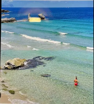 a woman standing in the water at the beach at La casa di Angy in Terrasini
