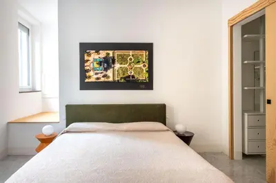 a bedroom with a bed and a picture on the wall at Sartoria Cavour - Modern Sicilian Elegance in a Former Tailor Shop in Palermo