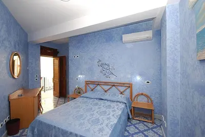 a bedroom with a bed in a blue room at Hotel Il Melograno in San Vito lo Capo